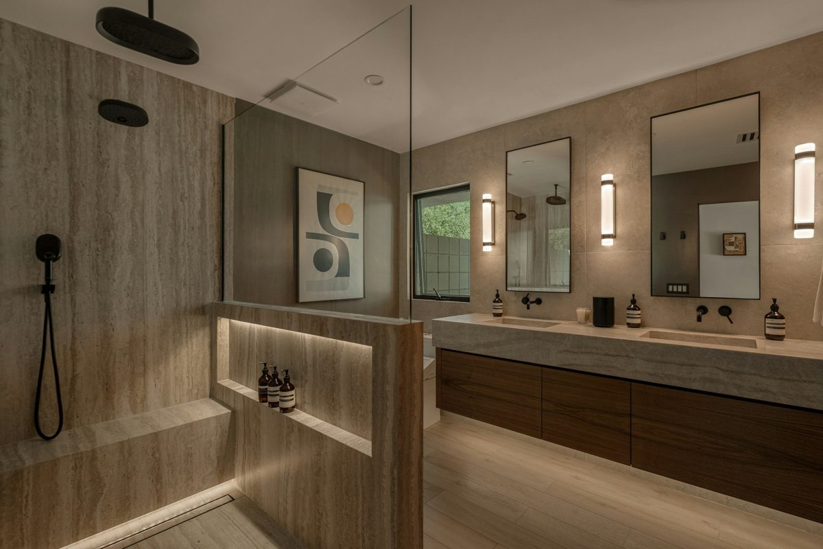 Baño con doble lavamanos, gavetas de madera y espejos iluminados