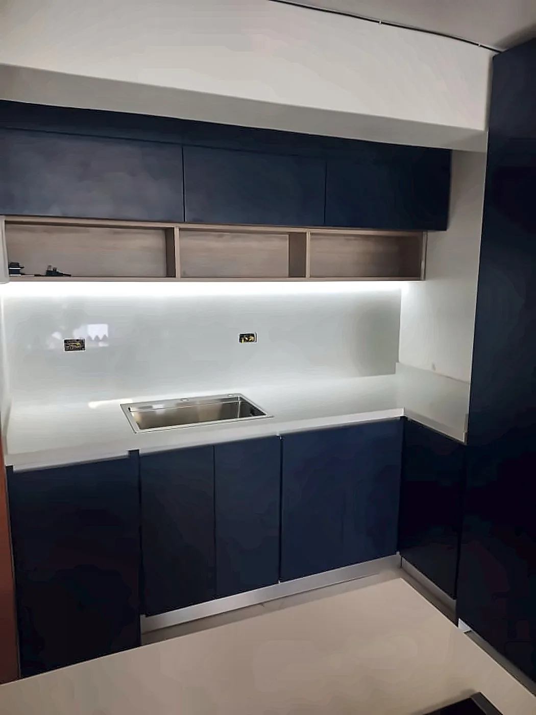 Frente azul con repisas de madera e iluminación LED